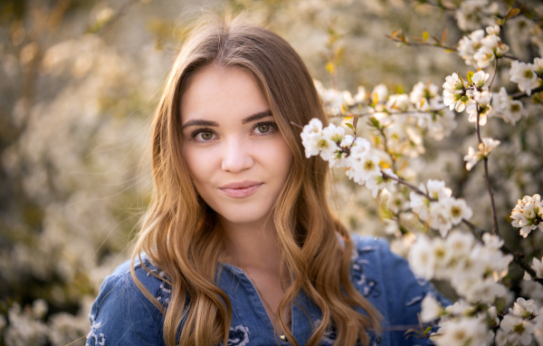 Красивая девушка у ветки с белыми цветами