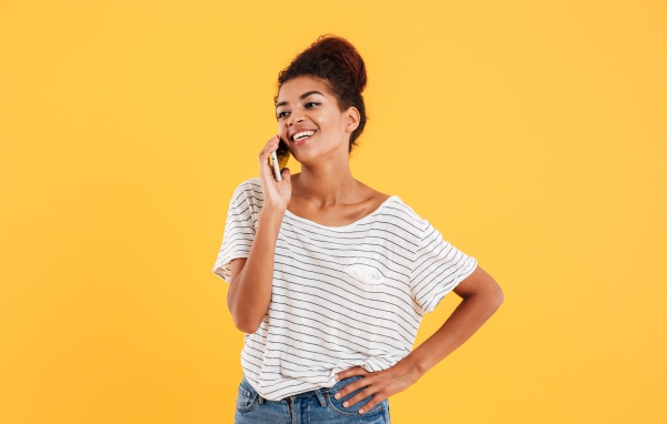 Красивая девушка со смартфоном на желтом фоне