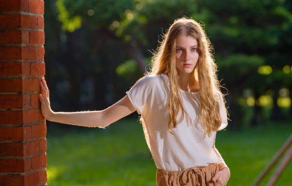 Красивая нежная девушка стоит у стены 