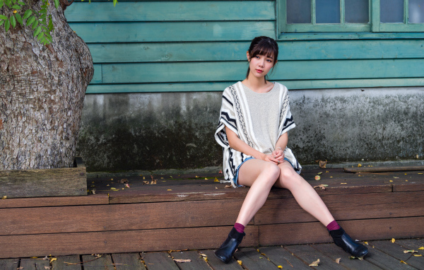 Красивая молодая девушка азиатка сидит у дома