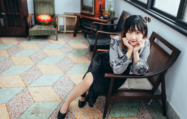 Красивая молодая азиатка сидит в кресле