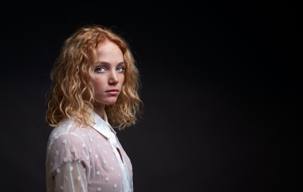 Голубоглазая девушка в белой рубашке на черном фоне