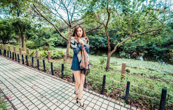 Милая девушка азиатка стоит в осеннем парке 