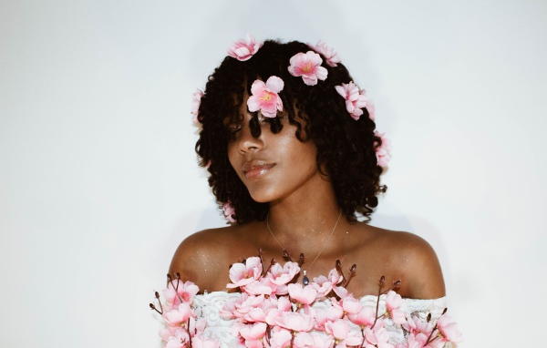 Темнокожая девушка в розовых цветах на сером фоне