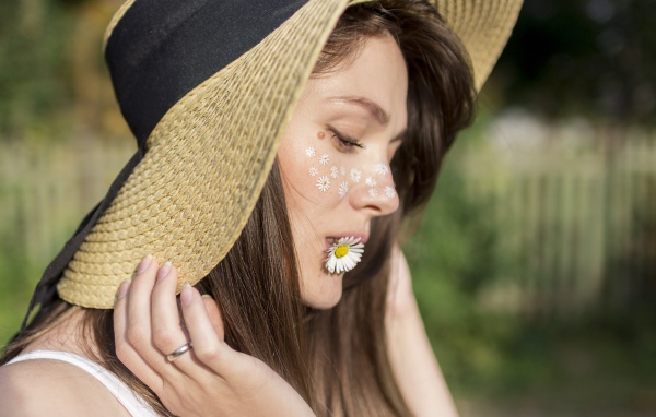 Девушка в шляпе с ромашкой в зубах 