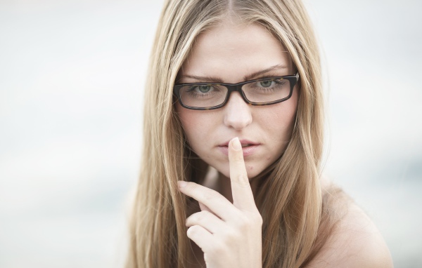 Девушка в очках с пальцем у лица