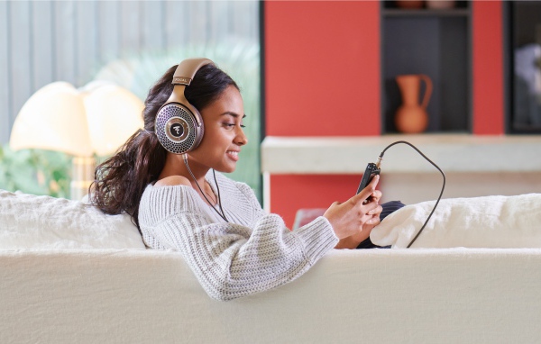 Девушка модель в наушниках на диване с плеером
