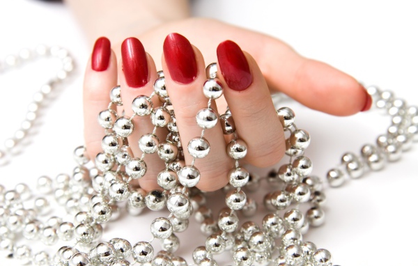 Девушка с красным маникюром с бусами в руке 