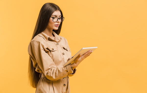 Девушка с планшетов руках на желтом фоне