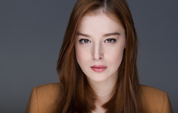 Рыжеволосая  молодая девушка на сером фоне