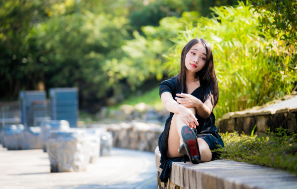 Грустная девушка в черном платье отдыхает в парке