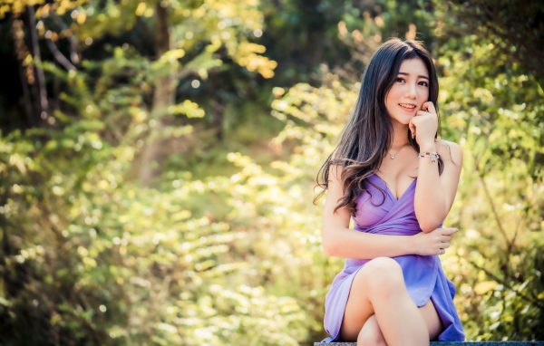 Улыбающаяся девушка азиатка в сиреневом платье