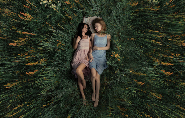 Две девушки лежат в высокой траве