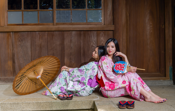 Две молодые девушки в кимоно сидят на полу