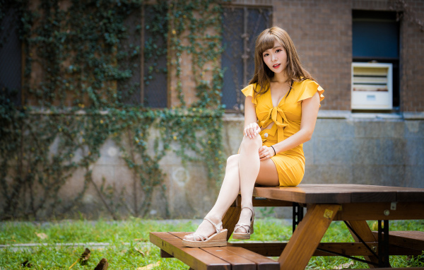 Молодая азиатка сидит в парке на столе 