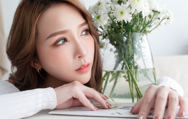 Молодая азиатка с букетом белой хризантемы в вазе