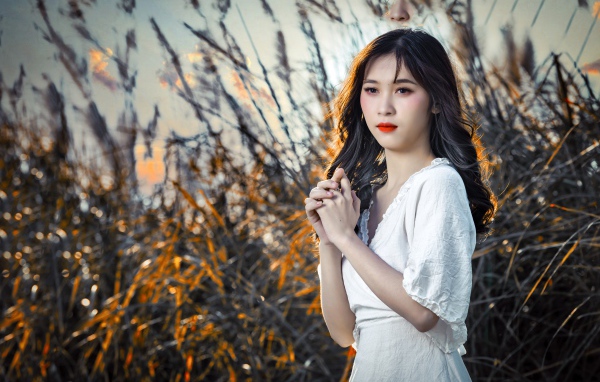 Молодая девушка азиатка в белом платье на закате