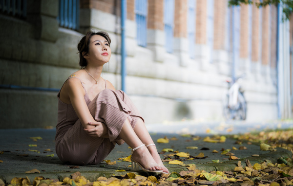 Молодая девушка азиатка сидит на земле с листьями 