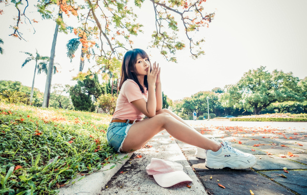 Молодая азиатка сидит на земле в осеннем парке