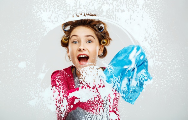 Молодая девушка в бигудях моет окно