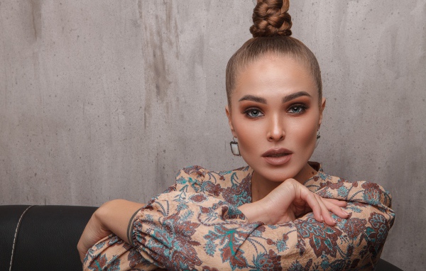 Молодая девушка с прической на голове на фоне стены