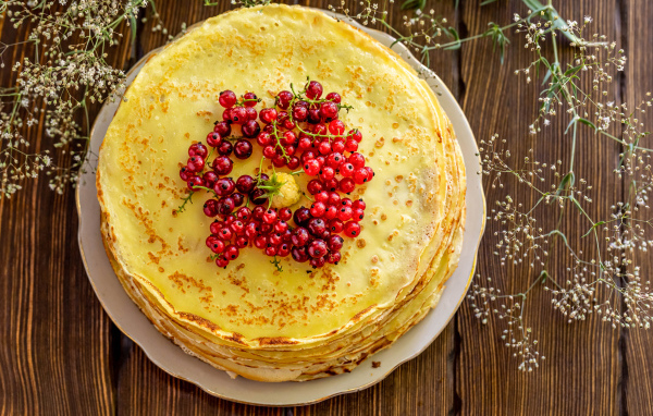 Аппетитные блины с ягодами красной смородины на столе 