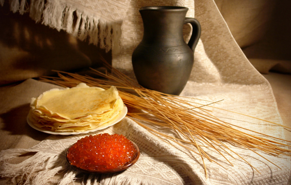 Блины с икрой на столе с колосьями на праздник Масленица