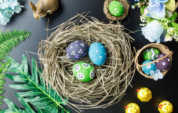 Яркие пасхальные яйца на столе в гнезде