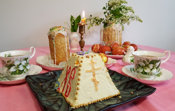 Творожная паска на столе с крашеными яйцами и чаем