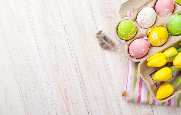 Крашеные пасхальные яйца на столе с тюльпанами