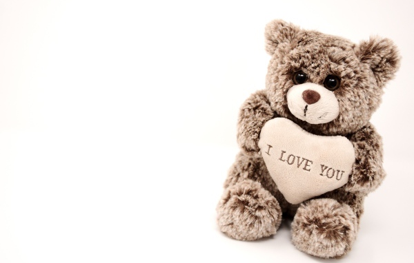 Меховая игрушка медвежонок с сердцем на белом фоне