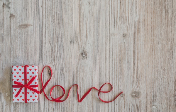 Коробка с подарком  и надпись любовь красной лентой на деревянном фоне