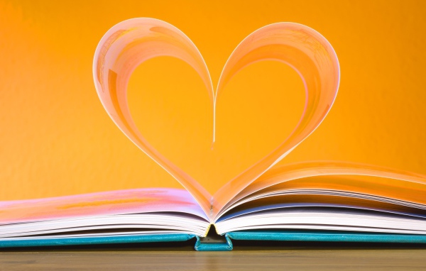 Сердце из страниц книги на оранжевом  фоне  