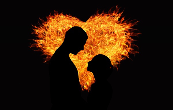 Влюбленная пара на фоне огненного сердца на черном фоне