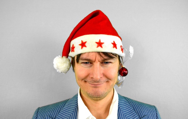 Голубоглазый мужчина в новогодней шапке на сером фоне 