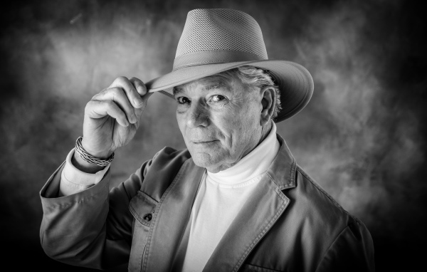 Пожилой мужчина в шляпе на фоне дыма 