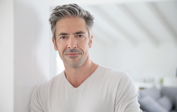 Седой стильный мужчина у стены