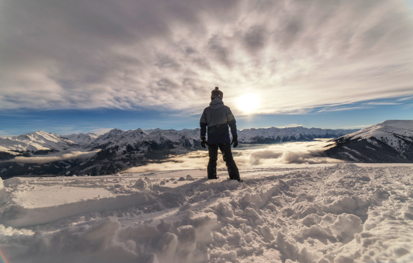 Человек в заснеженных горах в лучах солнца