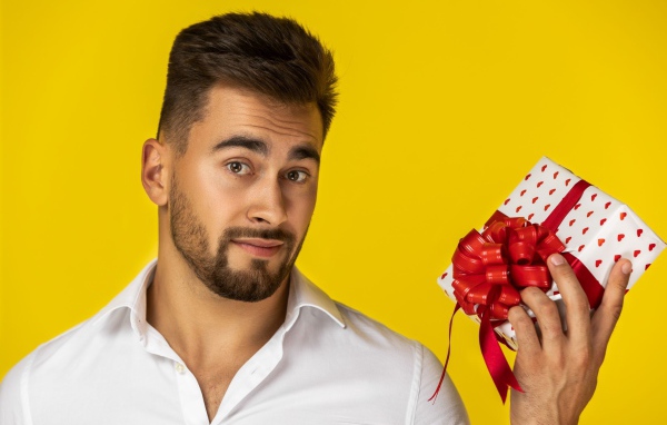 Мужчина с подарком на желтом фоне 