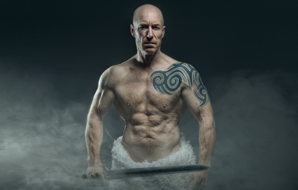 Сильный мужчина с мечом с татуировками на теле 