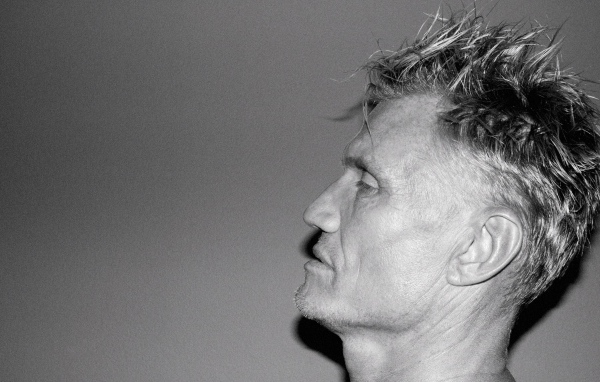 Лицо актера Дольфа Лундгрена боком на сером фоне