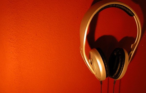 Большие золотые наушники на оранжевом фоне 