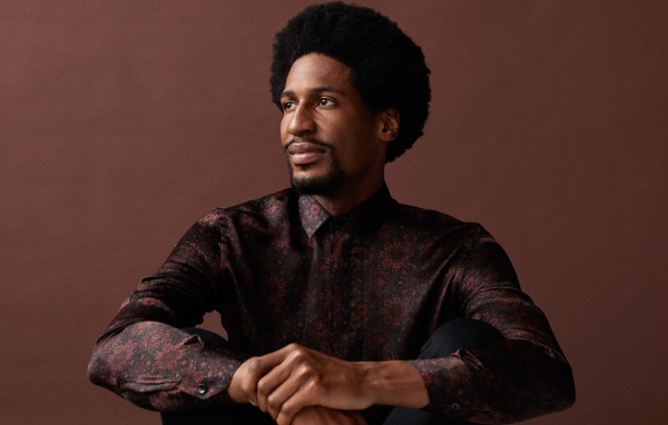 Музыкант Джонатан Батисте на коричневом фоне