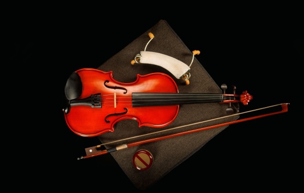 Red violin with bow on black background