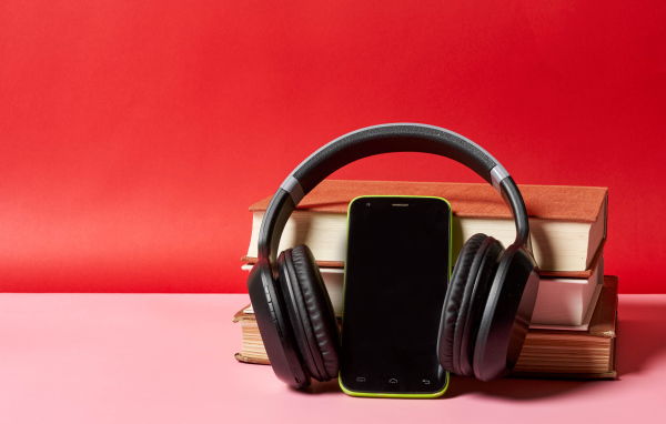 Смартфон, наушники и книги на красном фоне