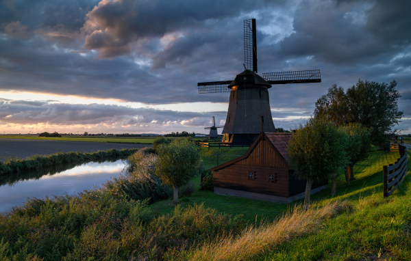 Large windmill by the river at sunset