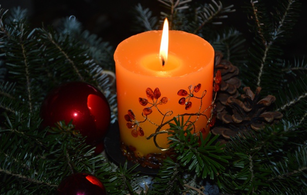 Зажженная свеча с ветками ели 