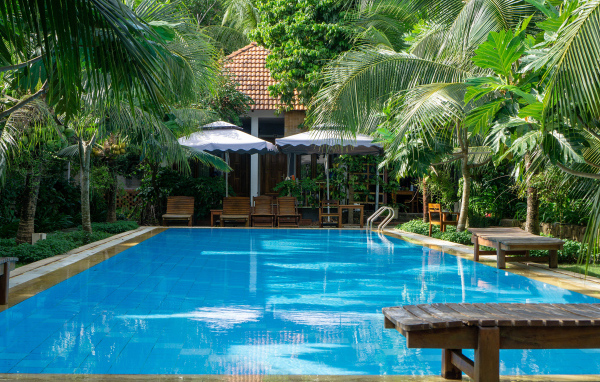 Бассейн с голубой водой у дома под пальмами