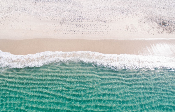 Белый морской песок на берегу у голубой воды