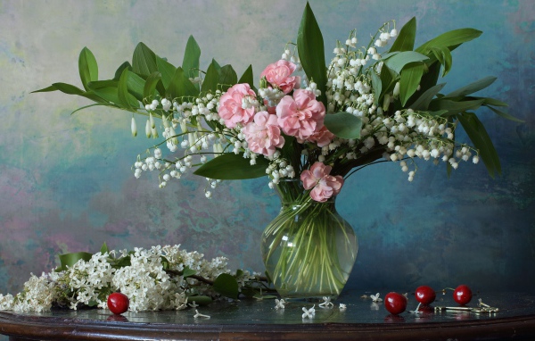 Красивый букет ландышей с розовыми цветами на столе с веткой сирени 